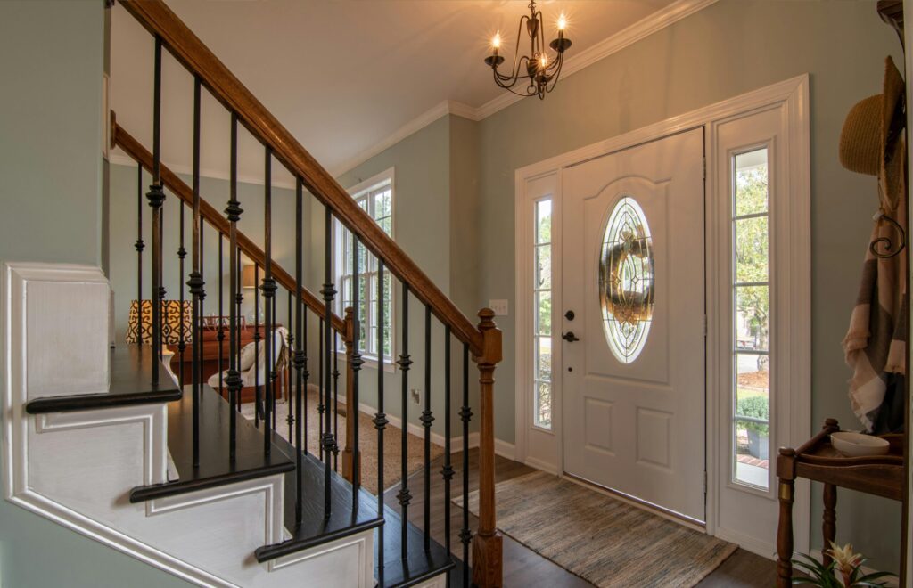 Inviting modern hallway with staircase, chandelier, and natural daylight.